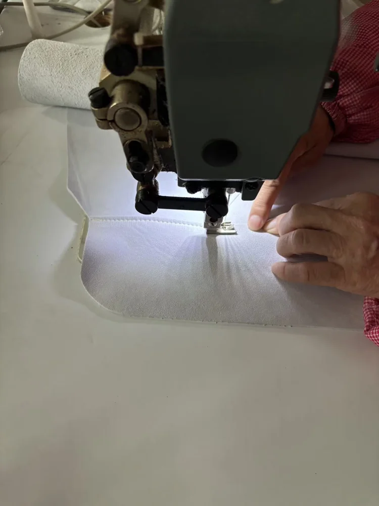 A close-up of leather material being worked at a sewing station.